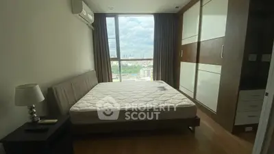 Spacious bedroom with large window offering stunning city view and ample natural light.