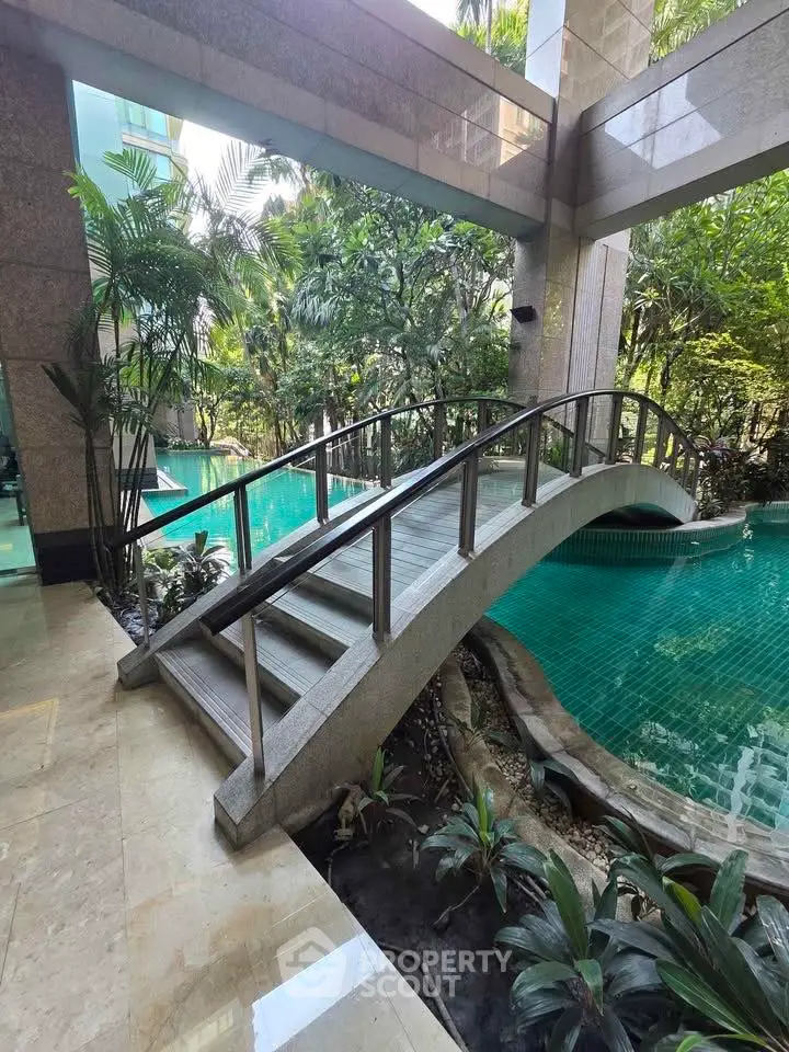 Luxurious indoor pool with elegant bridge and lush greenery in a modern real estate setting.