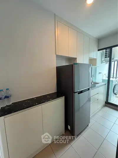 Modern kitchen with sleek cabinetry and stainless steel fridge in a bright apartment.