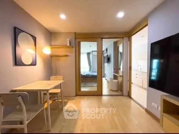 Modern apartment interior with open layout, featuring a cozy dining area and view into a stylish bedroom.
