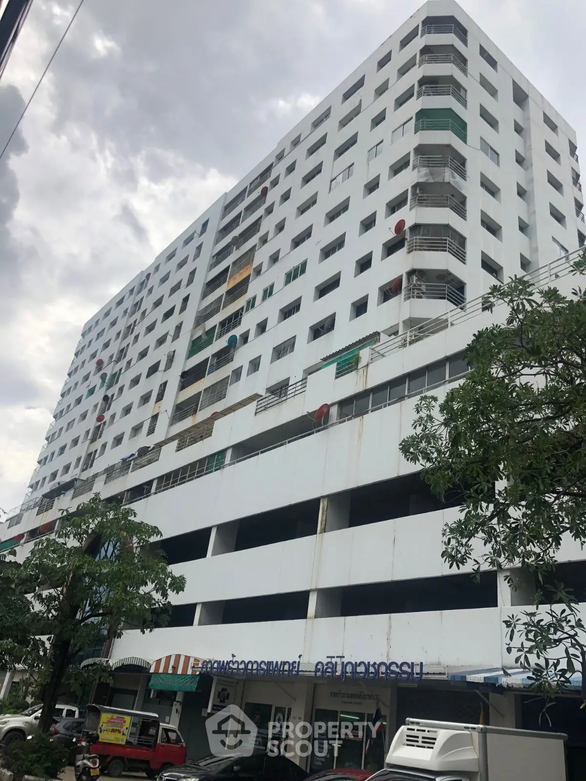 High-rise residential building with multiple balconies and street-level shops.