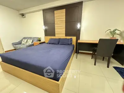 Spacious bedroom with modern design, featuring a comfortable bed, cozy sofa, and a functional study desk.