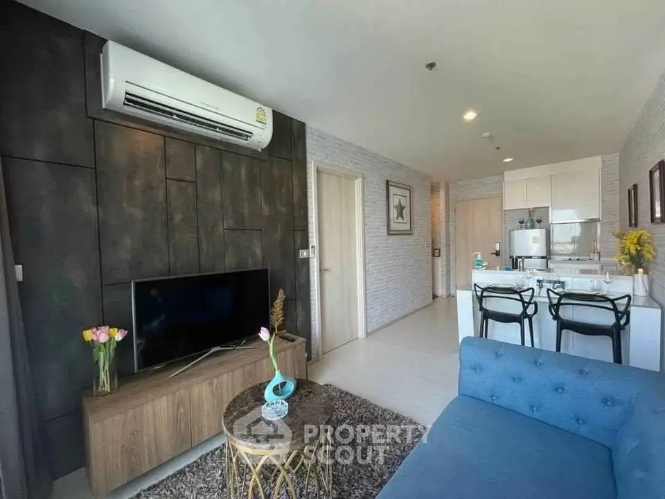 Modern living room with open kitchen, stylish decor, and air conditioning in a cozy apartment.