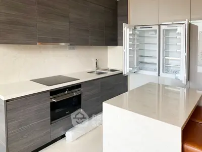 Modern kitchen with sleek cabinetry, built-in oven, and spacious fridge in a luxury apartment.