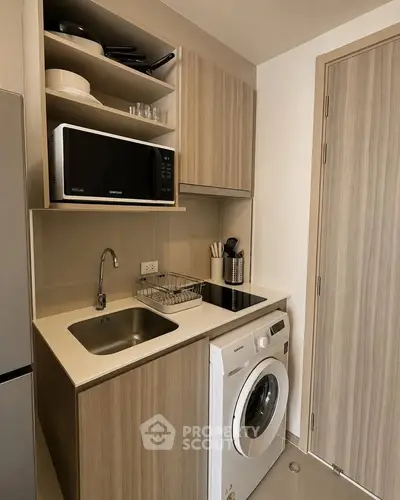 Compact kitchen with modern appliances including microwave and washing machine, ideal for small spaces.
