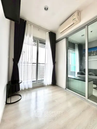 Spacious modern living room with balcony access and sleek glass doors in a high-rise apartment.