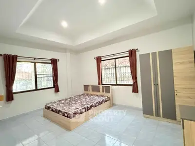 Spacious bedroom with modern furniture and large windows for natural light.