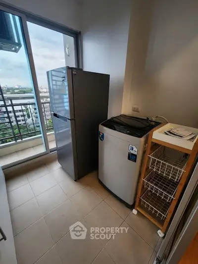 Modern laundry area with washing machine and fridge, featuring a balcony view in a high-rise apartment.