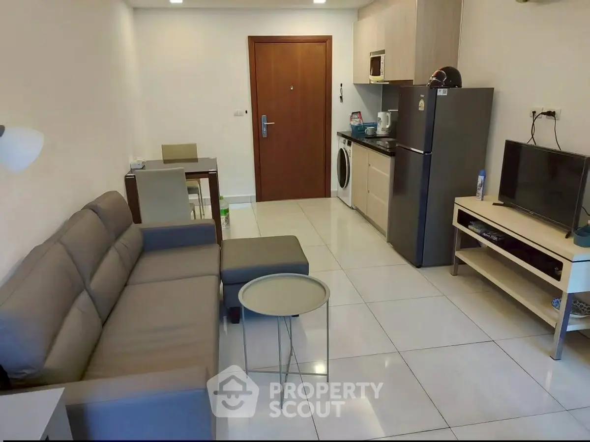 Modern living room with sleek kitchen, cozy sofa, and dining area in compact apartment.