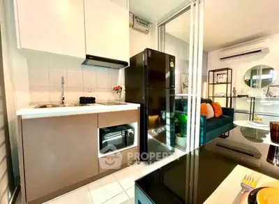 Modern kitchen with sleek appliances and cozy living area in open layout apartment.
