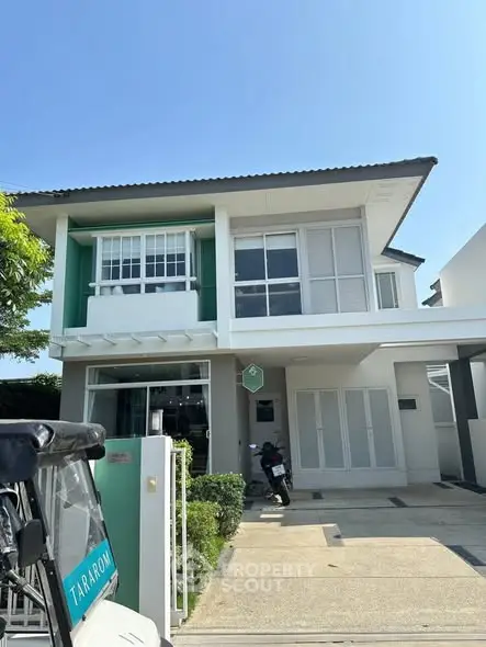 Modern two-story house with green accents and driveway parking