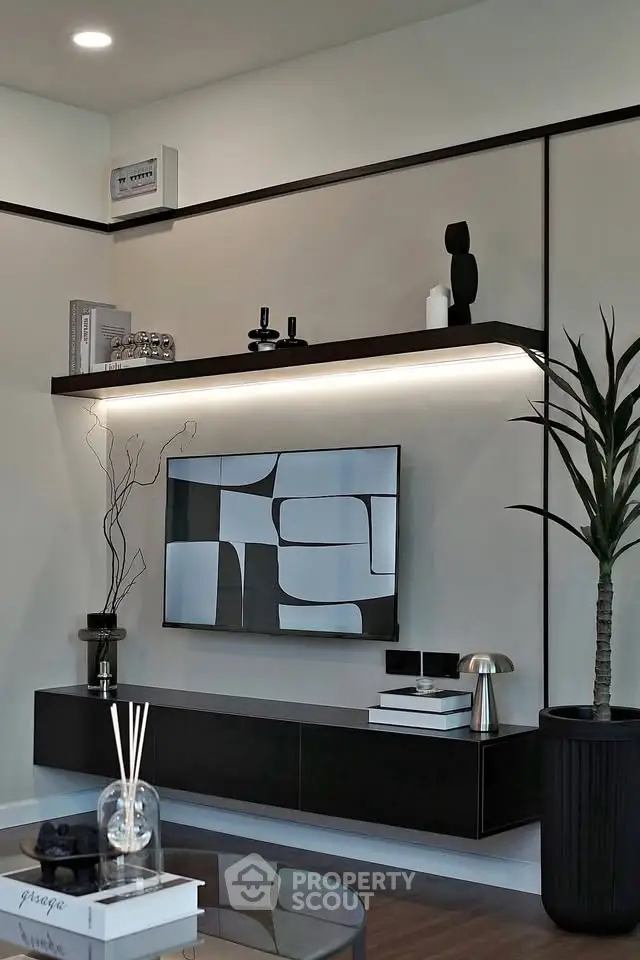 Modern living room with sleek black furniture and abstract art, featuring stylish decor and ambient lighting.