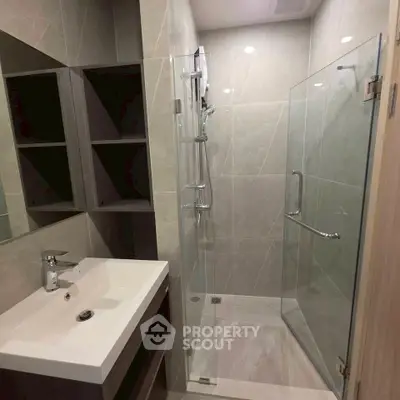 Modern bathroom with glass shower and sleek sink in contemporary apartment.
