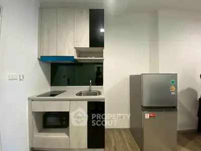 Modern compact kitchen with sleek cabinetry and stainless steel appliances in a cozy apartment.