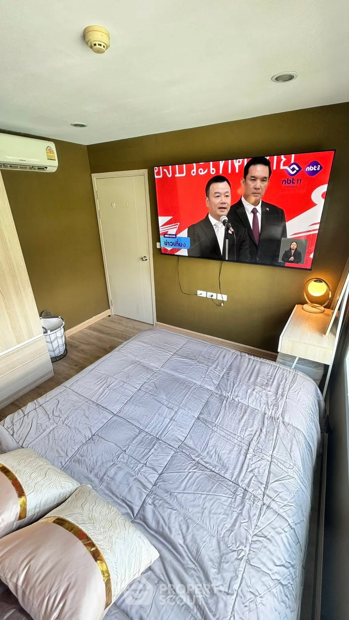 Cozy bedroom with wall-mounted TV and modern decor, featuring a comfortable bed and stylish lighting.