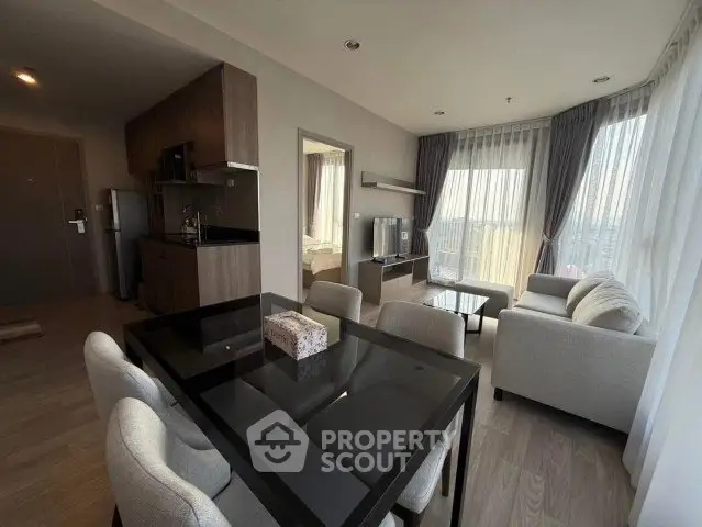 Modern open-plan living room with dining area and large windows offering city views.