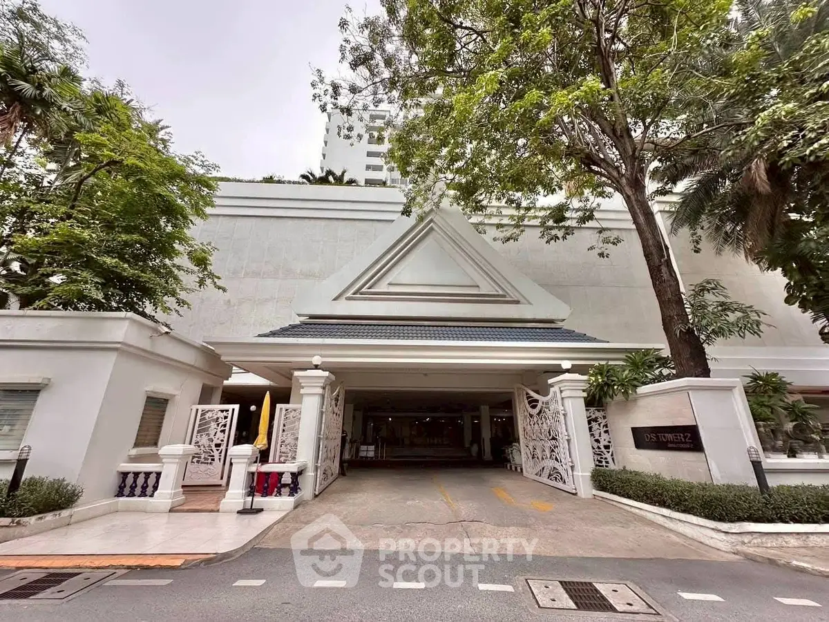 Elegant building entrance with lush greenery and modern architectural design.