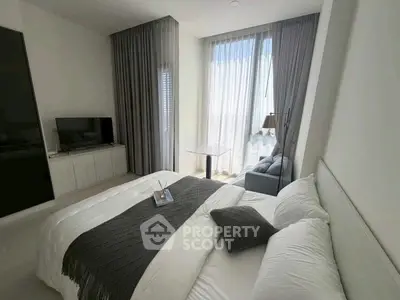 Modern bedroom with large window and cozy seating area, featuring elegant decor and natural light.