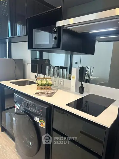 Modern kitchen with sleek black cabinetry, built-in microwave, and washing machine under counter.