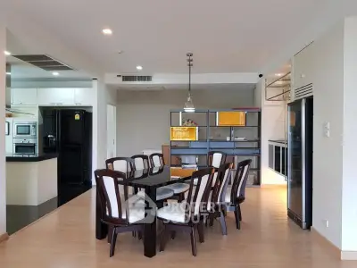 Spacious dining area with modern kitchen and elegant wooden furniture in open layout apartment.