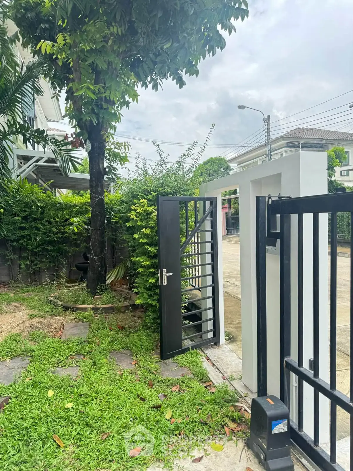 Charming garden entrance with modern gate and lush greenery, perfect for a welcoming home exterior.