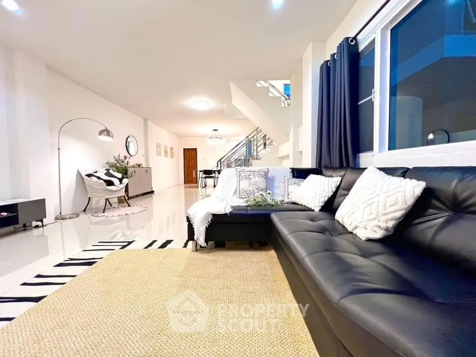 Spacious modern living room with sleek black leather sofa and stylish decor