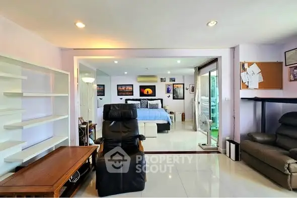 Spacious living room with modern decor and open view into a cozy bedroom