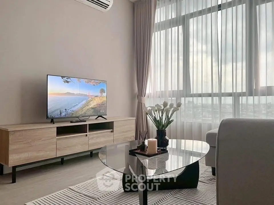 Modern living room with large window, stylish furniture, and scenic view on TV.