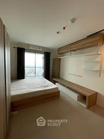 Modern bedroom with large window and built-in storage, offering ample natural light and sleek design.