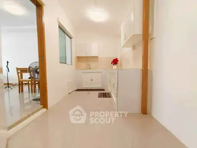 Bright kitchen with modern design and open layout, featuring sleek cabinetry and tiled flooring.