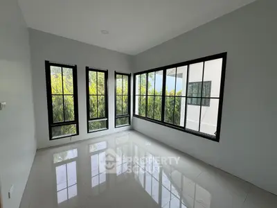 Spacious room with large windows offering lush green views, perfect for a serene living space.
