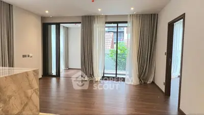 Spacious modern living room with wooden flooring and large windows for natural light.