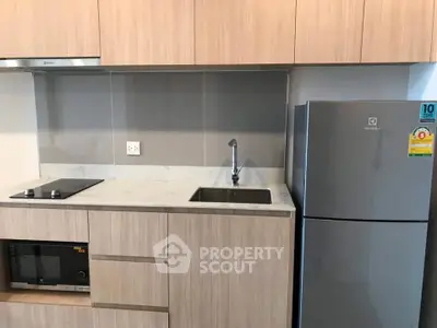 Modern kitchen with sleek cabinetry, built-in appliances, and a compact fridge for efficient space use.