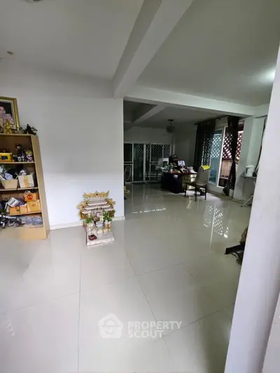 Spacious living area with tiled flooring and natural light, ideal for family gatherings.