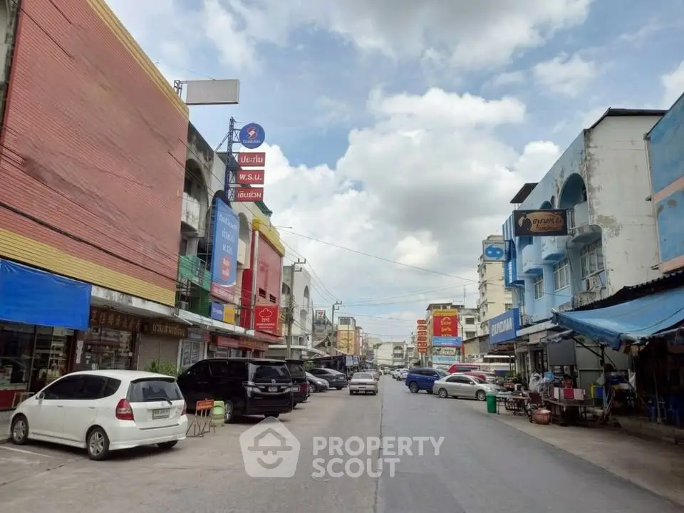 Vibrant street view with colorful buildings and parked cars under a bright sky.