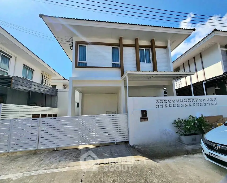 Modern two-story house with sleek design and gated entrance in a suburban neighborhood.