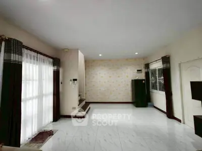 Spacious living room with large windows and elegant curtains, featuring modern tiled flooring and stylish wallpaper.