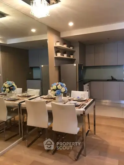 Modern dining area with elegant table setting and sleek kitchen in open layout apartment.