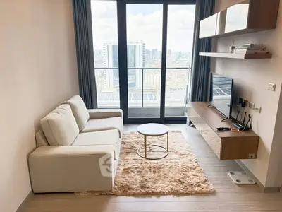Modern living room with city view, featuring a cozy sofa, stylish shelves, and a sleek TV setup.