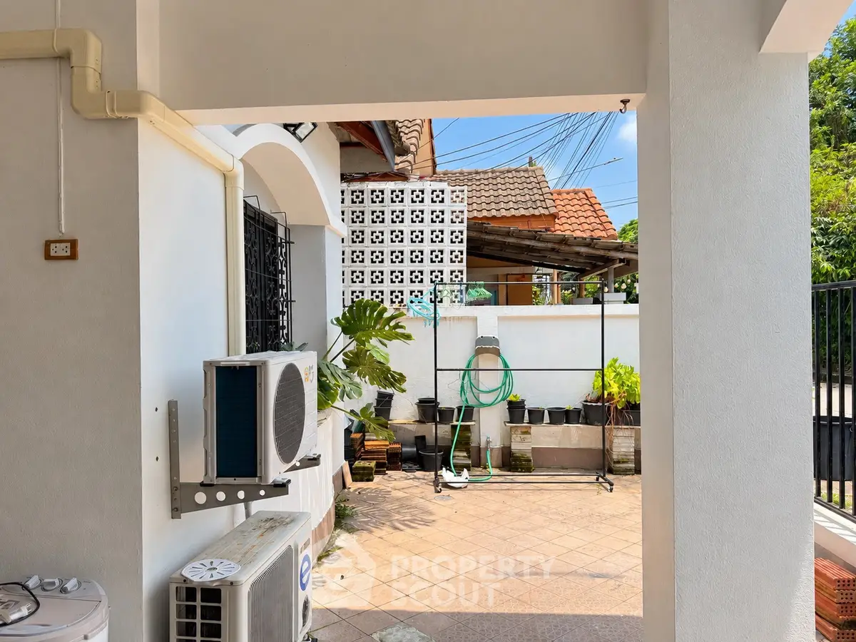Charming outdoor patio with air conditioning unit and garden area in a suburban home.