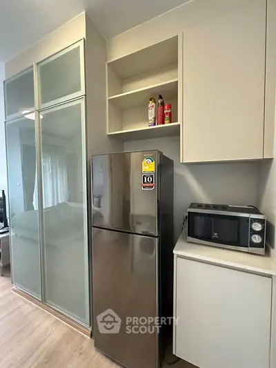 Modern kitchen with sleek fridge and microwave in compact apartment