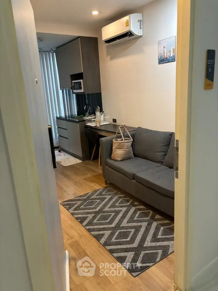 Cozy modern living room with sleek kitchen, featuring a comfortable sofa and stylish decor.