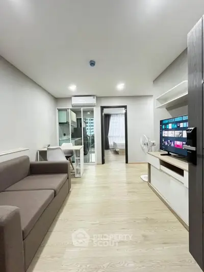 Modern living room with sleek furniture and open layout, featuring a cozy sofa and entertainment unit.