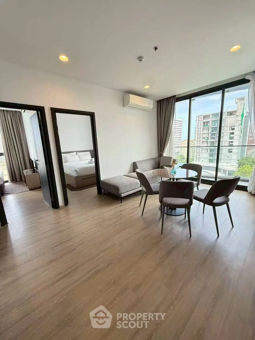 Spacious modern living room with large windows and city view, featuring elegant dining area and cozy seating.