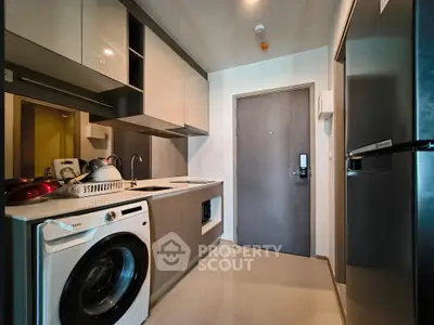 Modern kitchen with sleek appliances and washing machine in a compact layout.