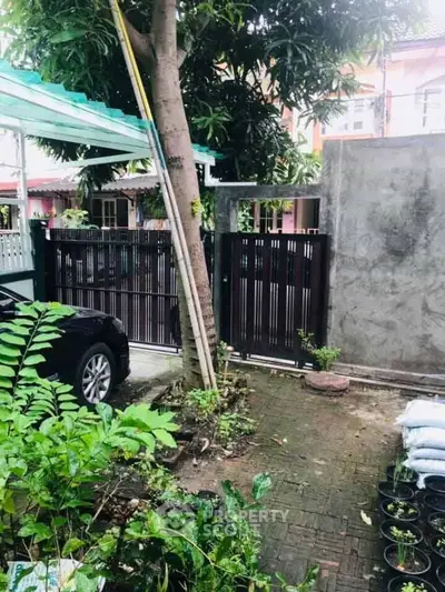 Charming garden area with lush greenery and secure gated entrance, perfect for relaxation and privacy.