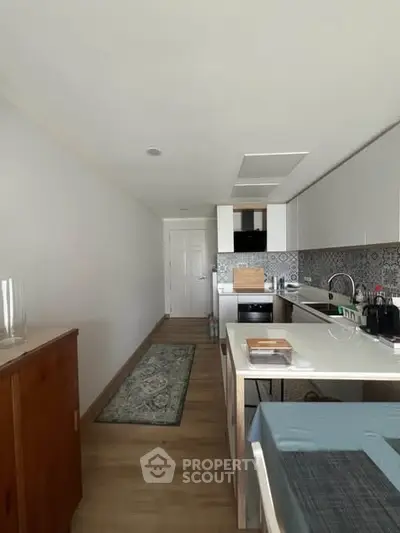 Modern kitchen with sleek cabinetry and open layout, featuring a stylish backsplash and integrated appliances.