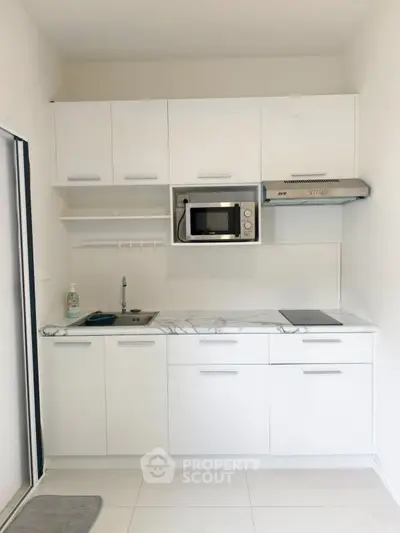Modern white kitchen with sleek cabinets and built-in microwave, perfect for contemporary living.