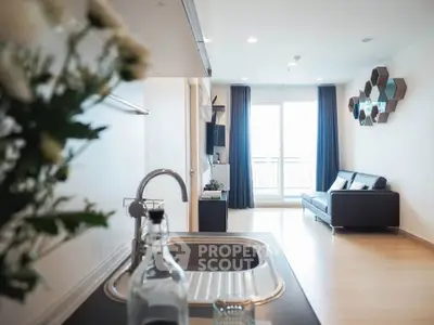 Modern open-plan living room with sleek kitchen and balcony view.