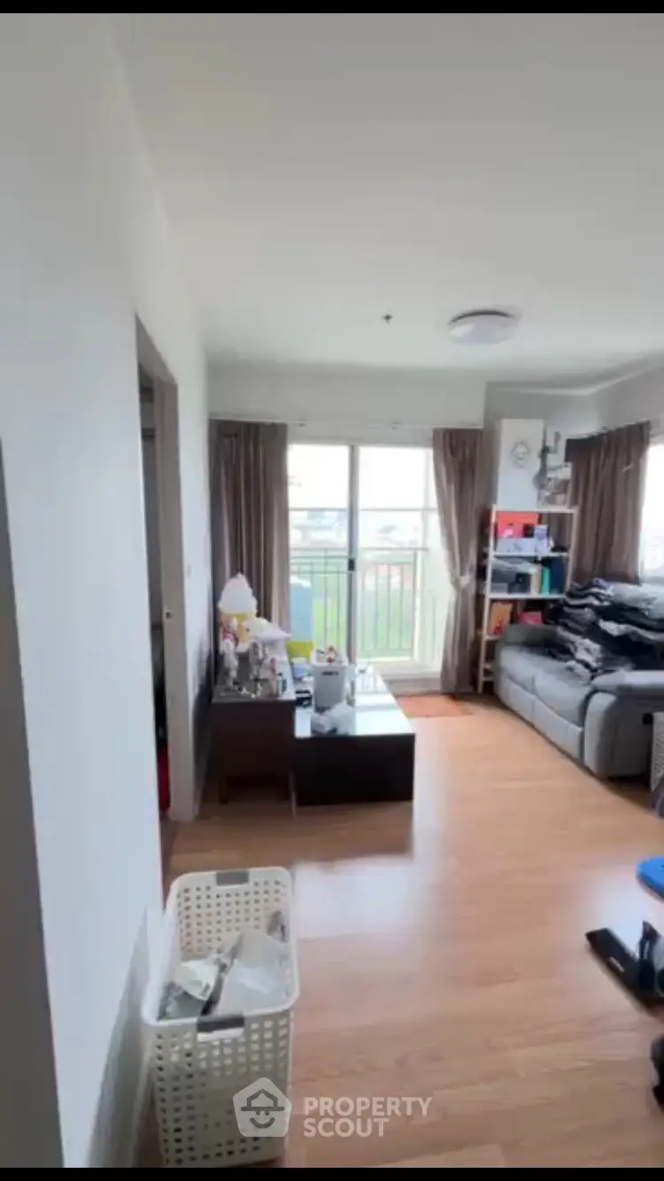 Bright living room with large window and cozy seating area in modern apartment.